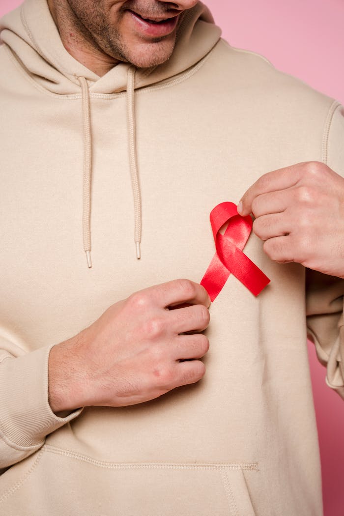 hero-img-01 Man in hoodie holding red ribbon symbolizing awareness and support.
